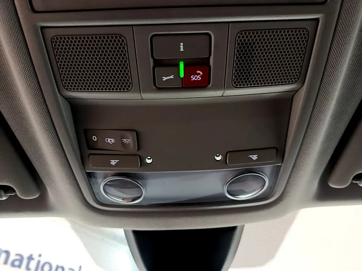 Vue en contre-plongée du panneau de commande au plafond intérieur du SEAT Ateca noir, avec bouton SOS rouge et éclairage intégré.