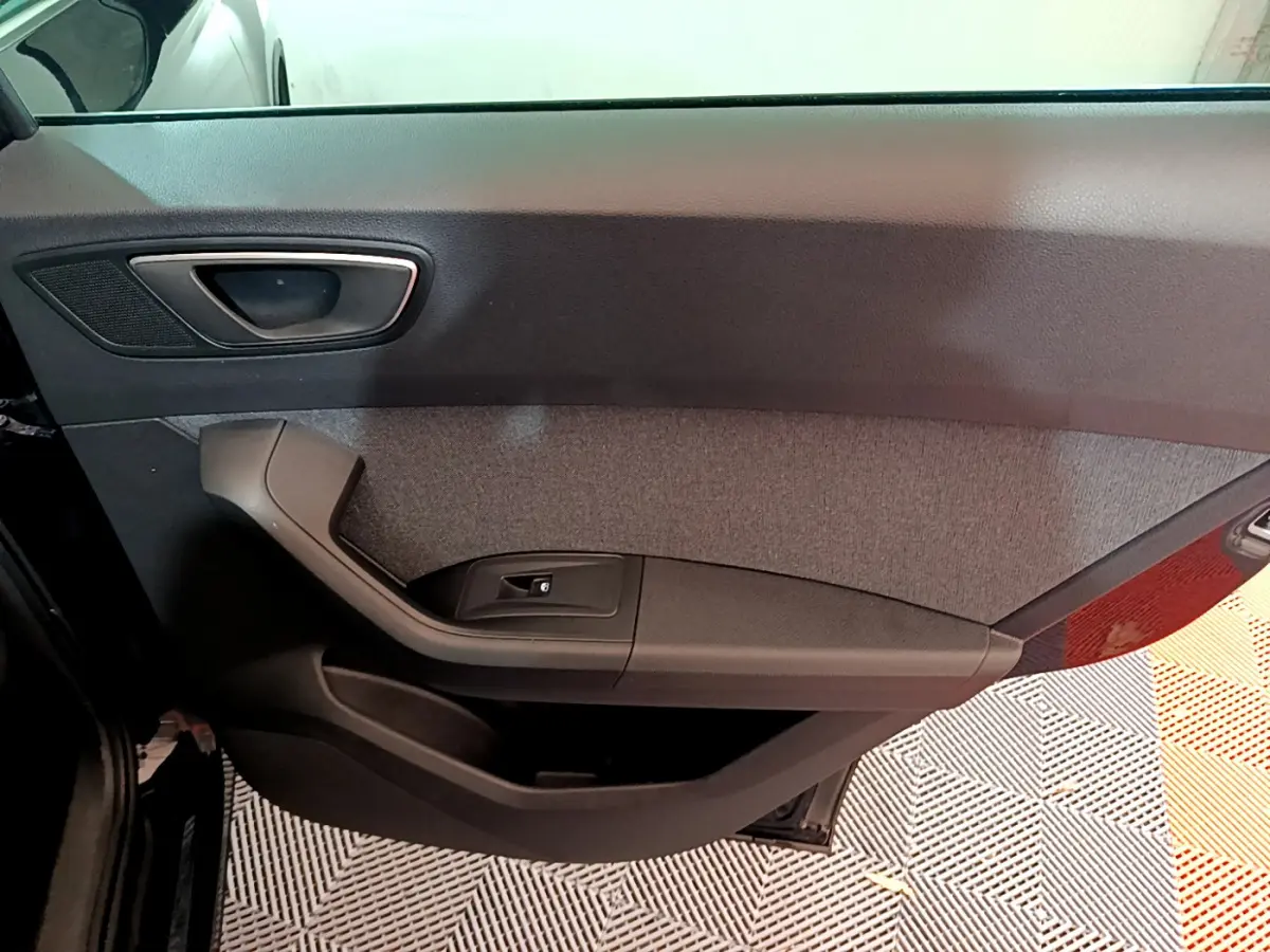 Vue intérieure du panneau de porte côté gauche du SEAT Ateca noir, avec poignée et commande de lève-vitre intégrée.