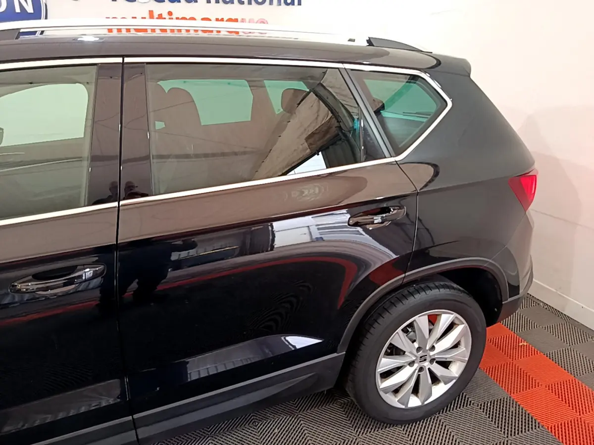 Profil arrière droit d'un SUV SEAT Ateca noir brillant avec jante alliage et poignées de porte chromées.