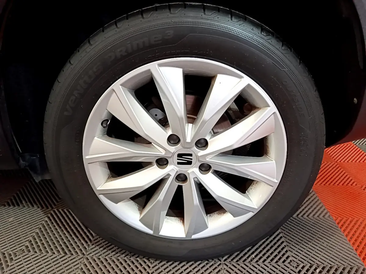 Gros plan sur la jante argentée du côté avant droit d'un SEAT Ateca noir, mettant en valeur le logo central SEAT.