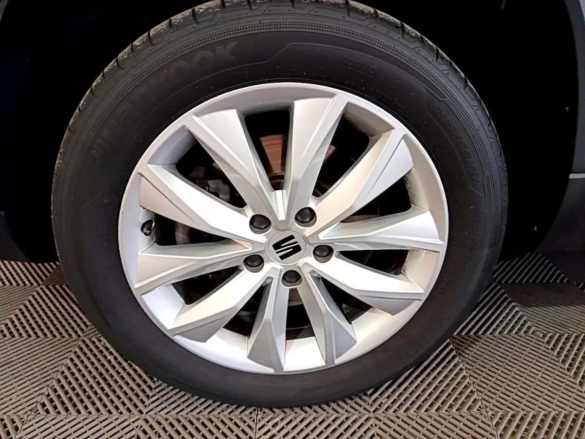 Gros plan sur la roue avant droite en alliage argenté du SEAT Ateca noir, mettant en valeur le logo central.