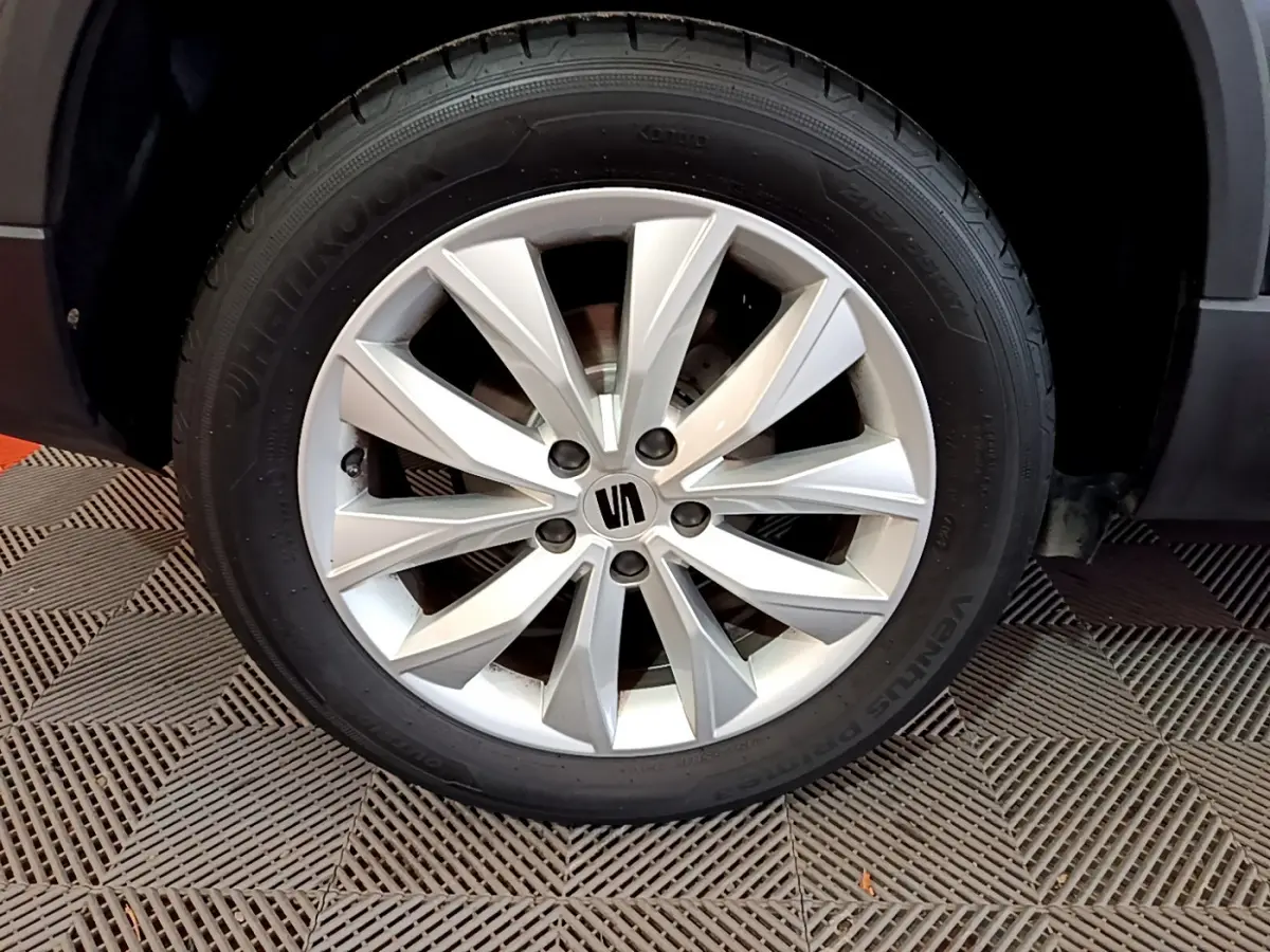 Gros plan sur la roue avant droite du SEAT Ateca noir 2022, mettant en valeur la jante alliage argentée au design moderne.