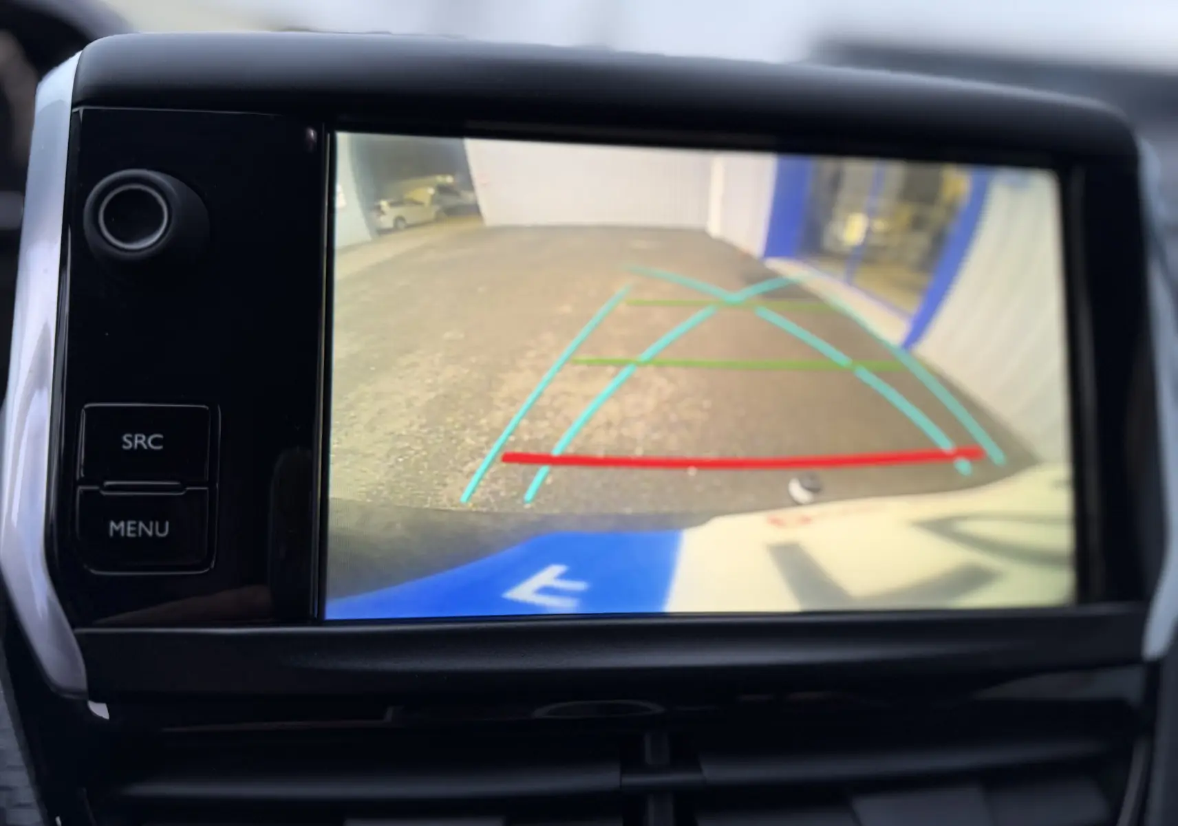 Écran de caméra de recul du Peugeot 2008 noir, vue arrière avec lignes de guidage colorées sur sol goudronné.