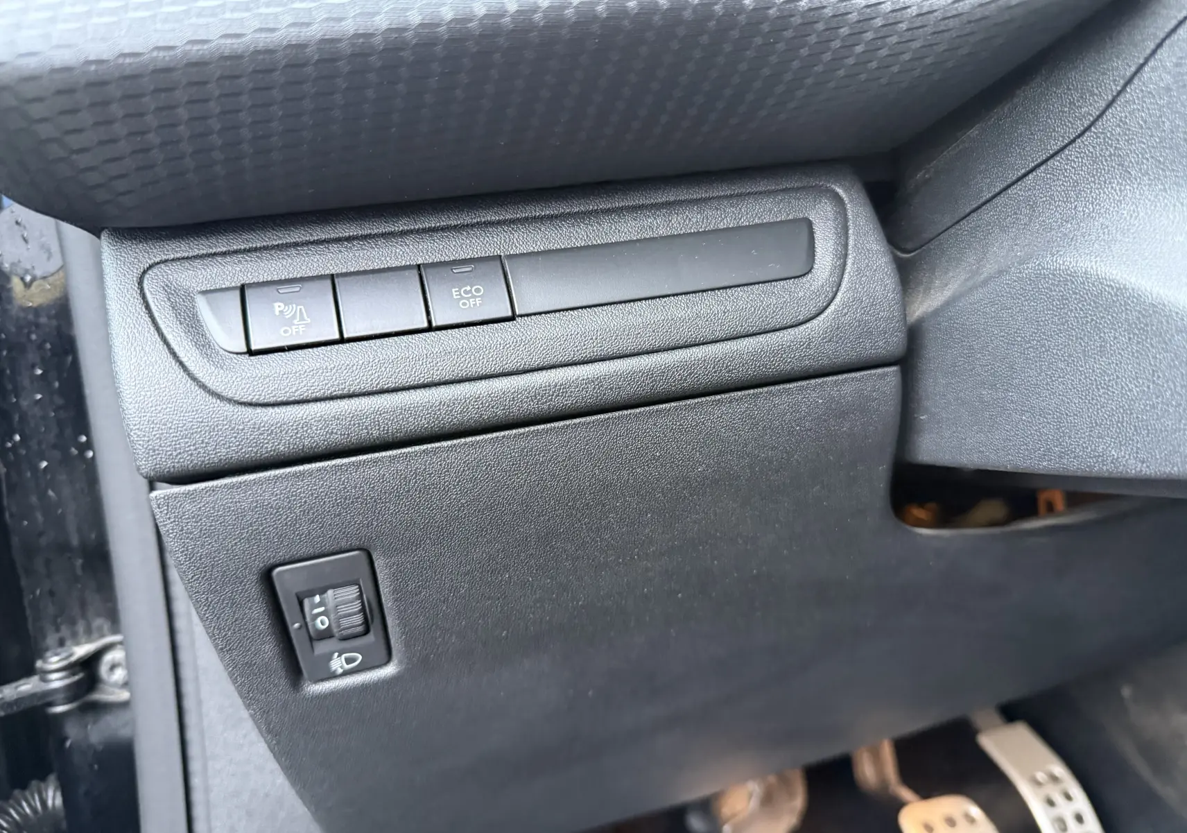 Vue intérieure côté gauche du tableau de bord noir du Peugeot 2008 GT Line 2018, avec boutons de contrôle et pédales visibles.