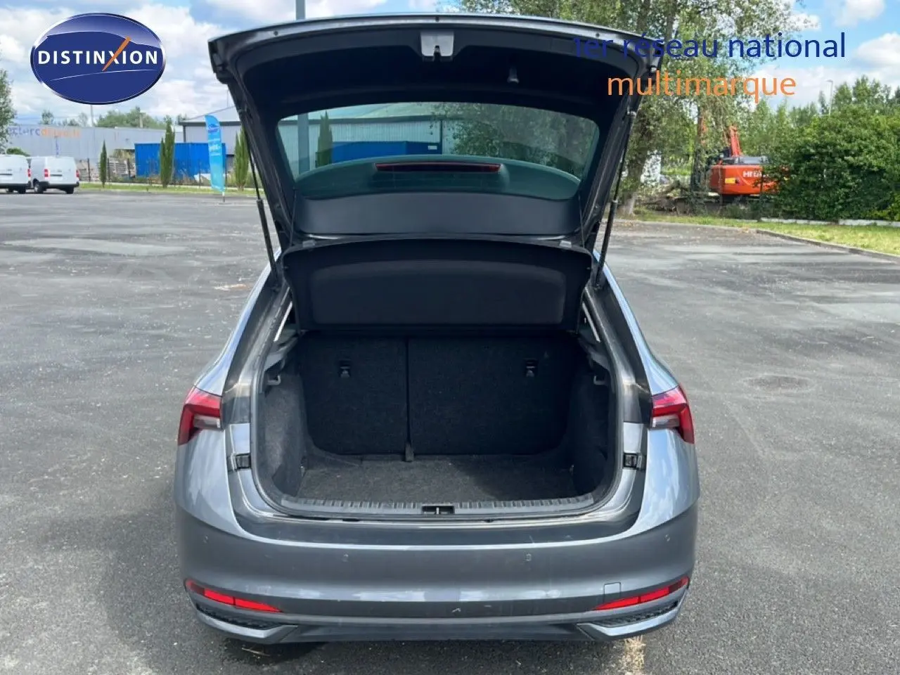 Vue arrière d'une Skoda Scala gris graphite métal avec coffre ouvert sur un parking extérieur.