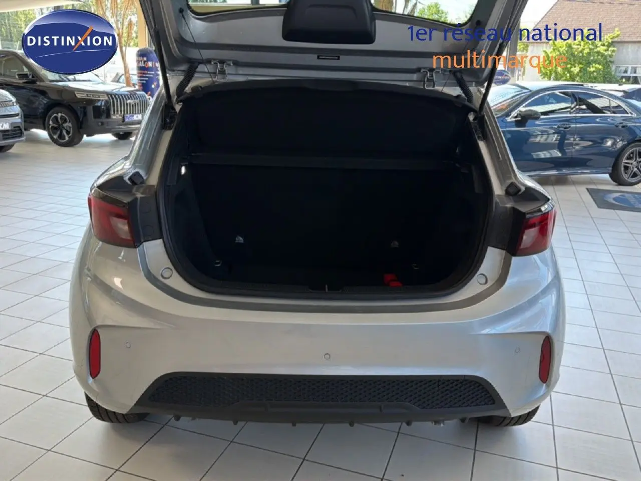 Vue arrière d'une MG3 1.5L Hybrid+ 195CH Luxury en Cosmic Silver Metal avec coffre ouvert dans un showroom.