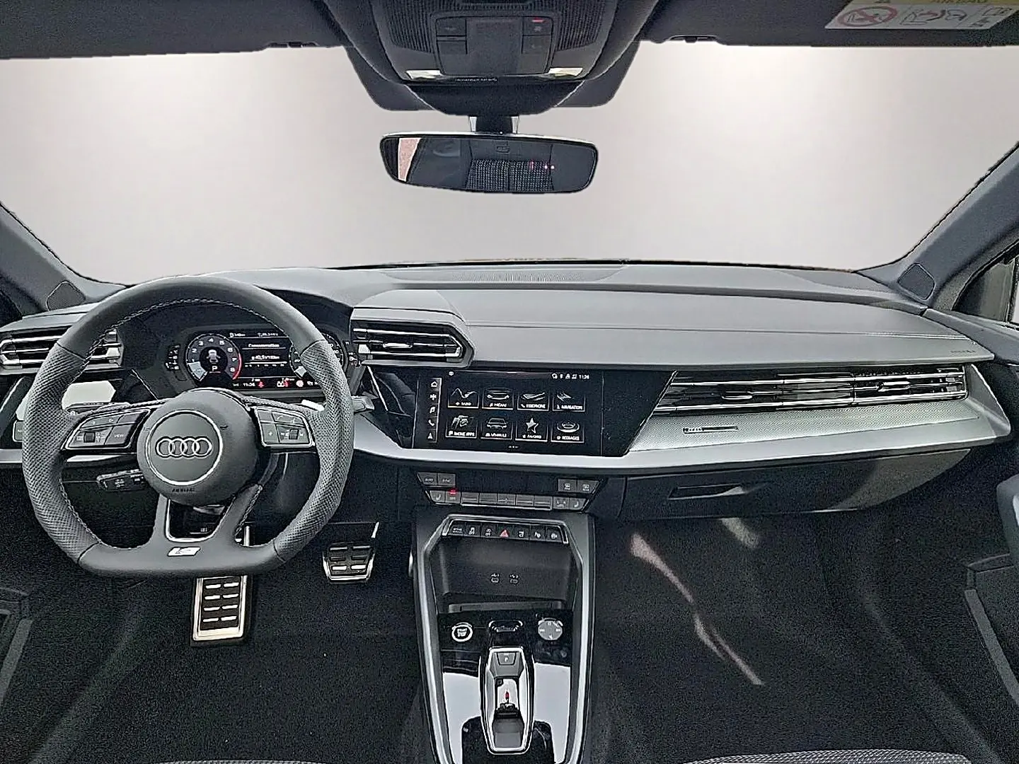 Vue intérieure avant de l'Audi A3 Sportback 2026 avec tableau de bord noir, volant sport multifonction et écran tactile central.