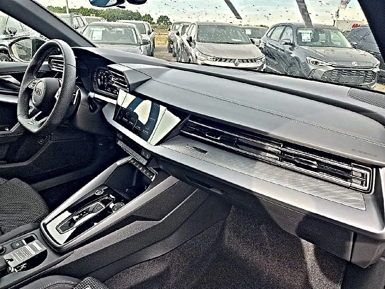 Vue intérieure côté conducteur de l’Audi A3 Sportback 2026 avec tableau de bord noir et écran tactile central.