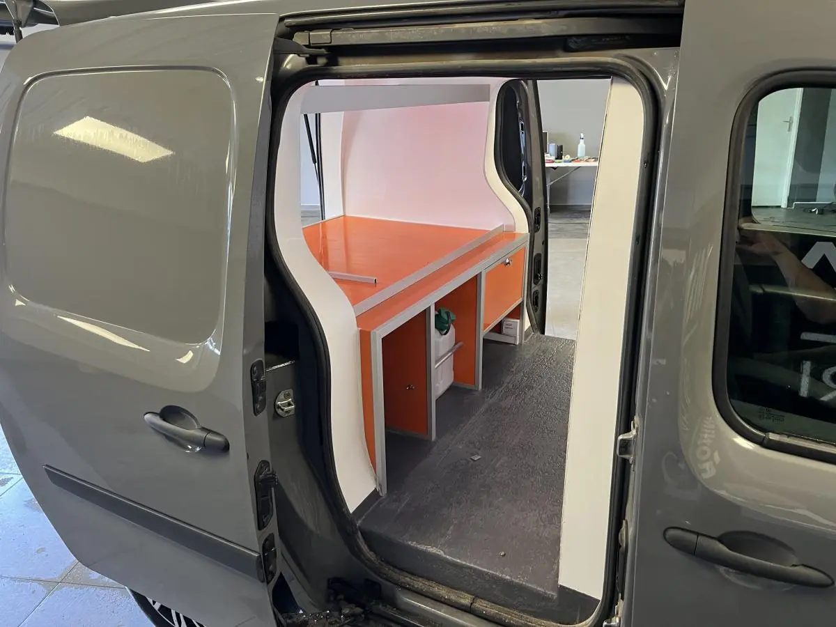 Vue côté gauche du Renault Kangoo Express gris foncé avec porte coulissante ouverte et aménagement intérieur orange visible