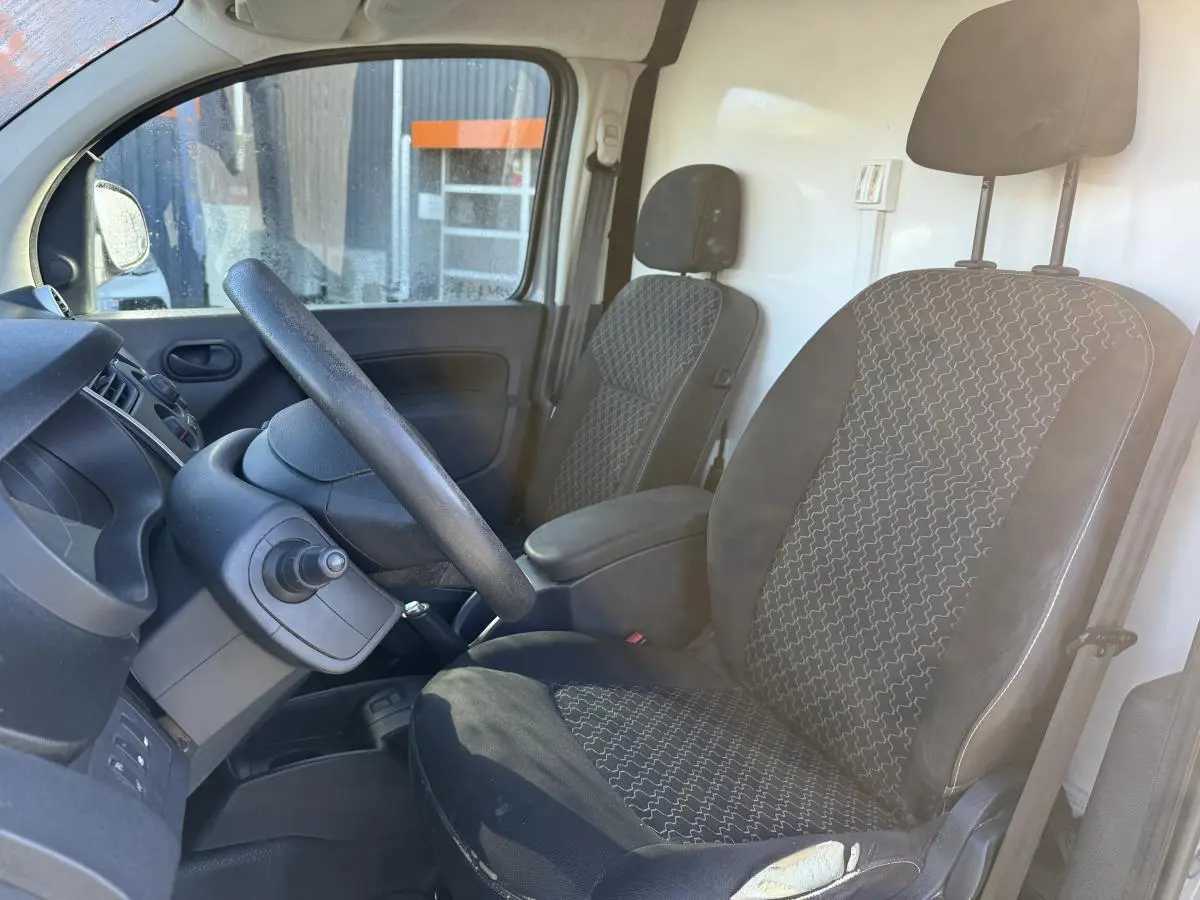 Intérieur du Renault Kangoo Express 2016, vue côté conducteur, sièges tissu noir à motifs gris et tableau de bord noir.