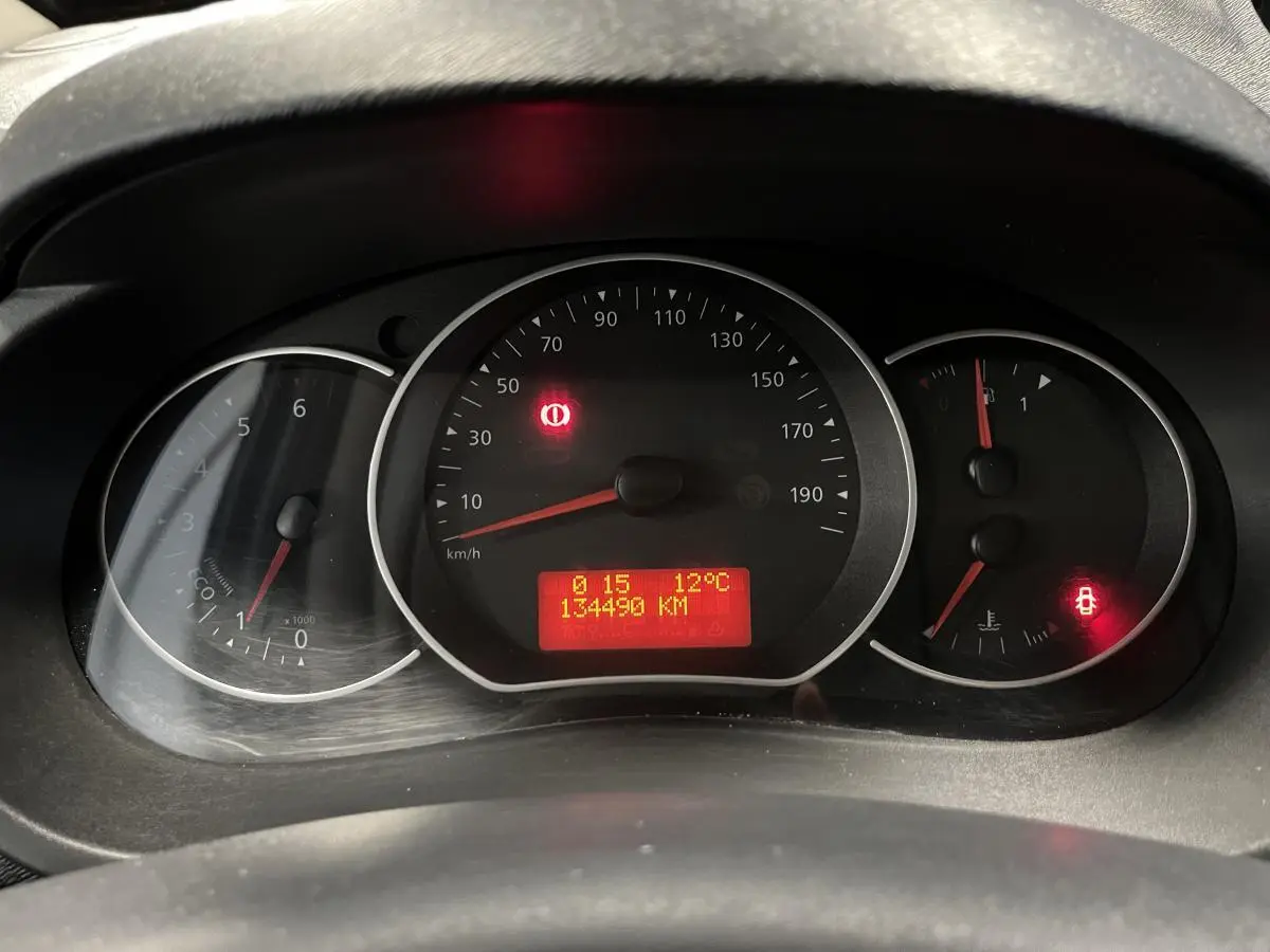 Vue rapprochée du tableau de bord noir du Renault Kangoo Express gris foncé, affichant 134490 km et témoins allumés.