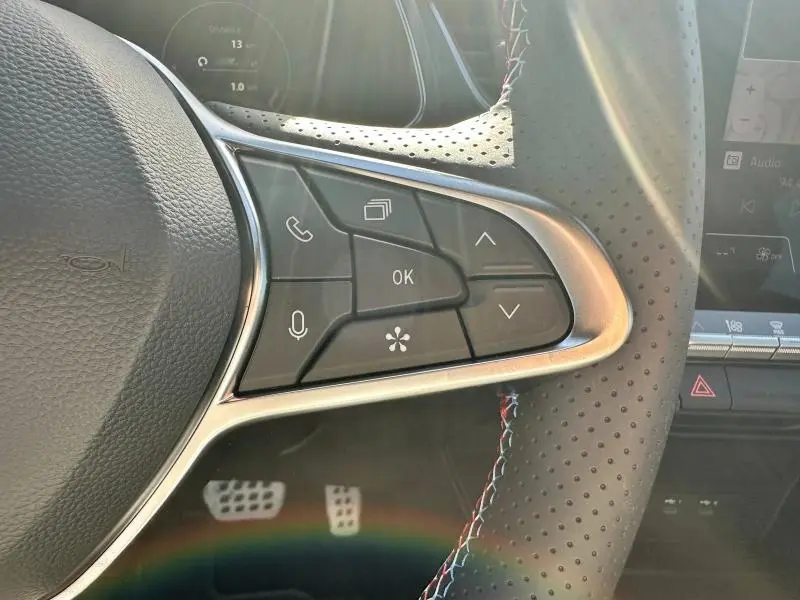 Gros plan sur les commandes multifonctions à droite du volant cuir perforé du Renault Captur rouge Flamme 2025 esprit Alpine.