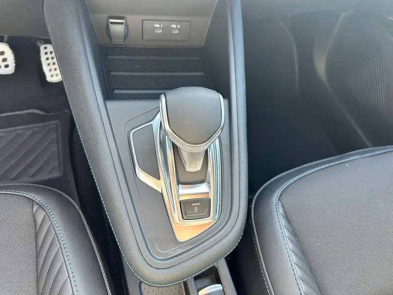 Le levier de vitesse automatique chromé et noir du Renault Captur 1.6 E-Tech, vu de dessus côté droit, avec sièges noirs.