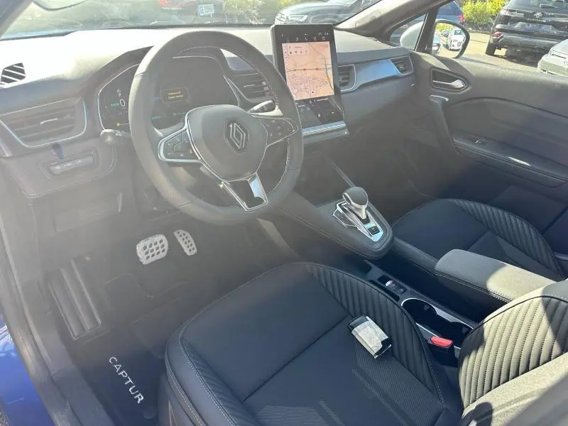 Intérieur noir du Renault Captur 2025, vue côté conducteur, volant cuir multifonction et écran tactile vertical.