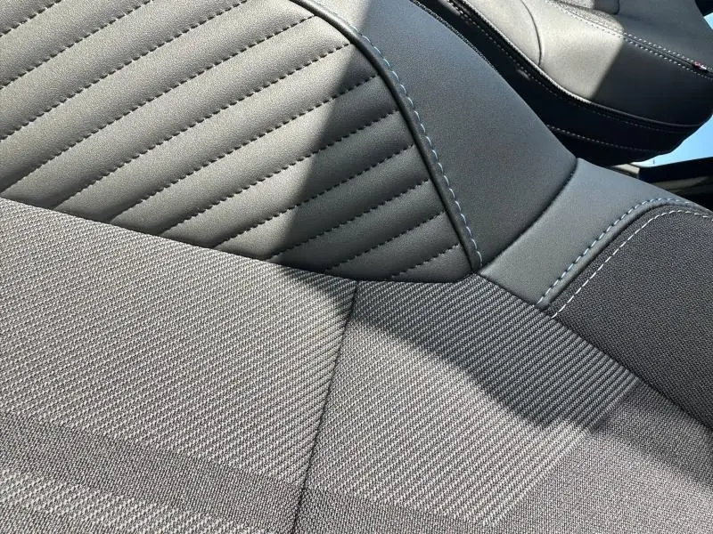 Gros plan sur la sellerie textile et cuir noir avec surpiqûres bleues du siège avant du Renault Captur 2025 esprit Alpine.