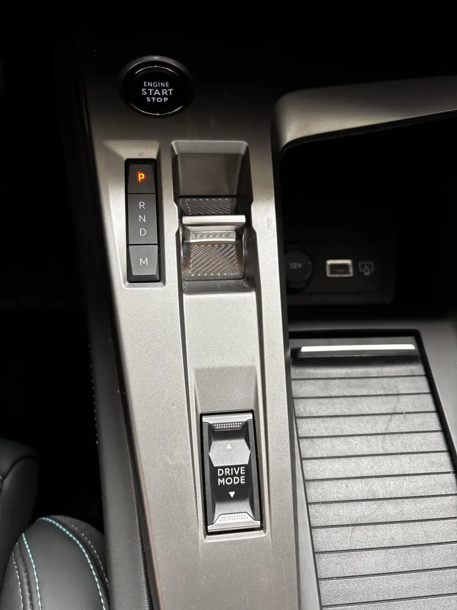 Gros plan sur la console centrale grise de la Peugeot 308 2024 avec bouton start/stop et sélecteur Drive Mode.