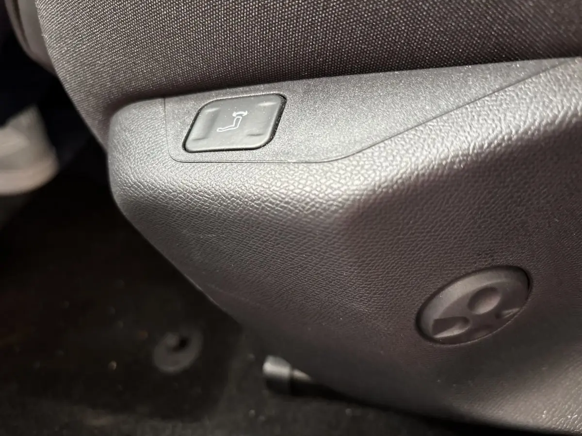 Bouton de réglage de siège en gros plan à l'avant droit d'un Peugeot 308 gris clair 2024.