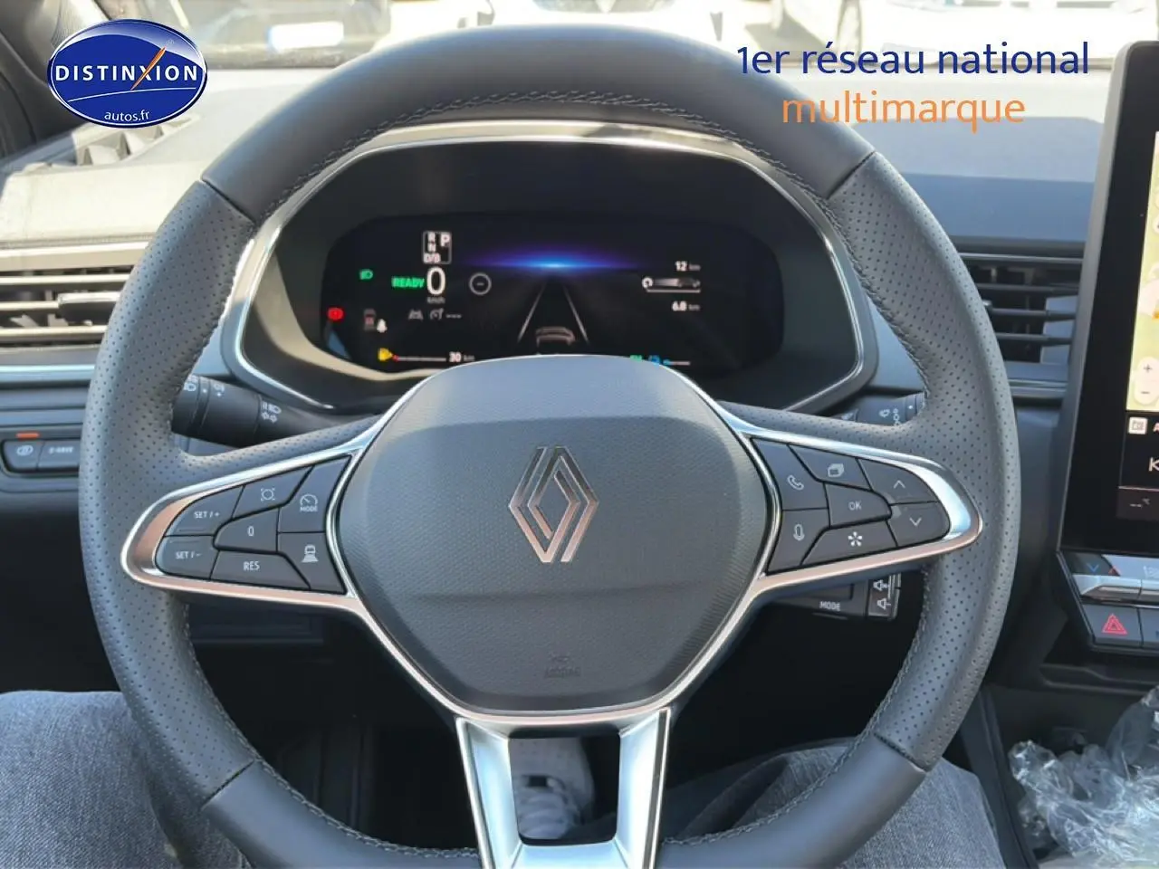 Vue rapprochée du volant multifonction noir avec logo Renault et tableau de bord numérique du Captur hybride 2026.