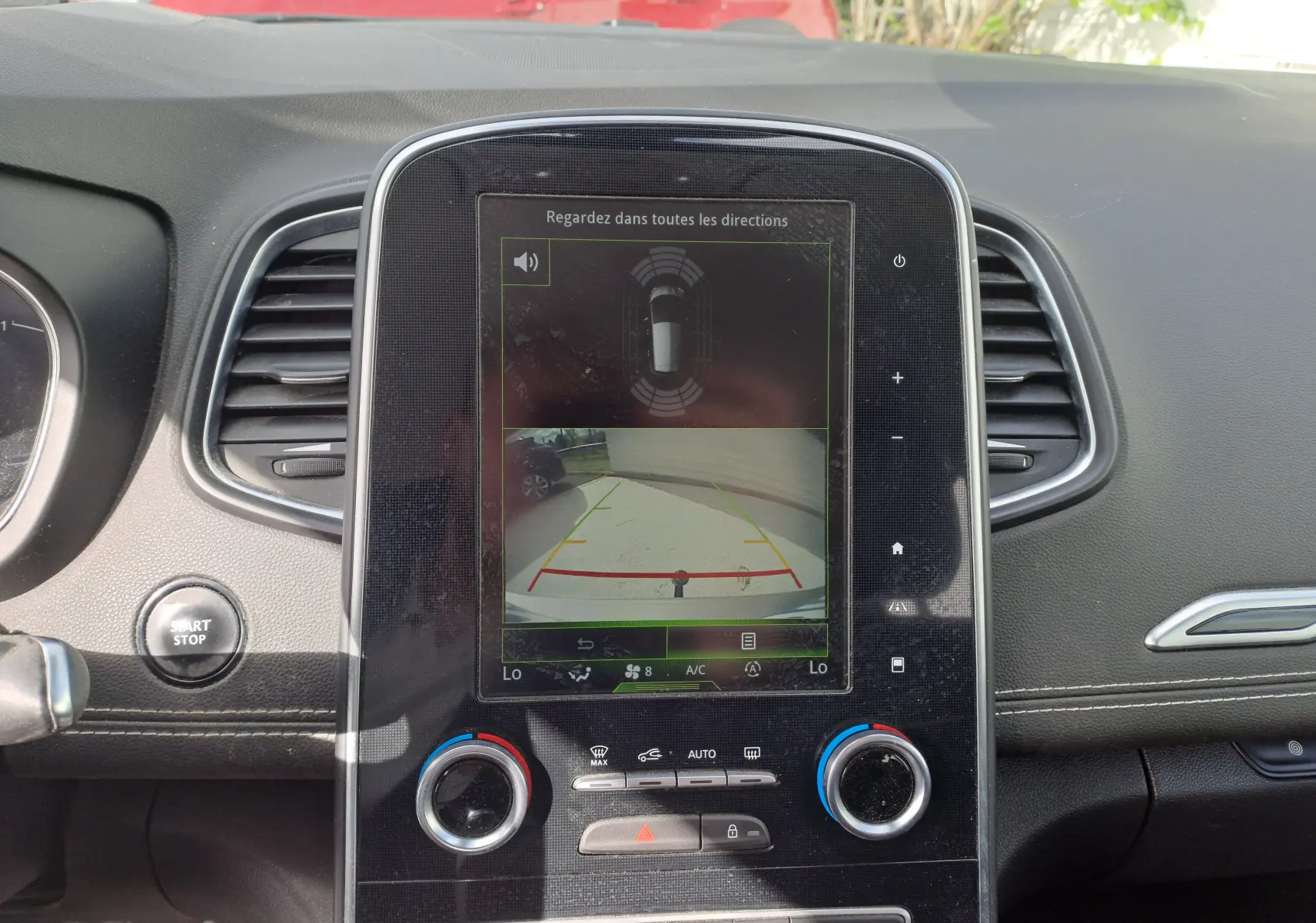 Écran central tactile affichant la caméra de recul et les capteurs de proximité dans le tableau de bord noir du Renault Scenic IV.