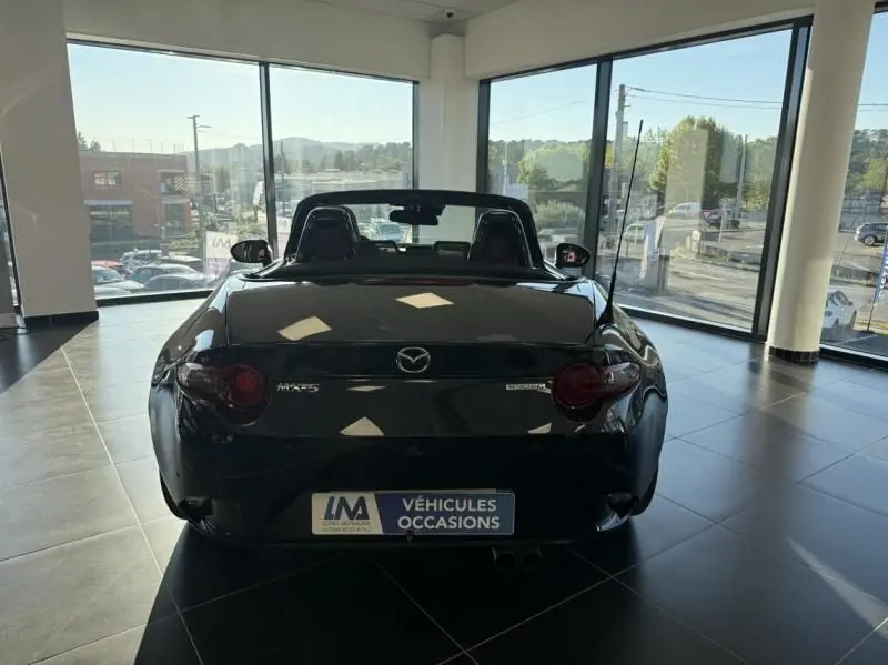 Vue arrière d'une Mazda MX-5 noire 2020 EUNOS EDITION, cabriolet, exposée en showroom lumineux.