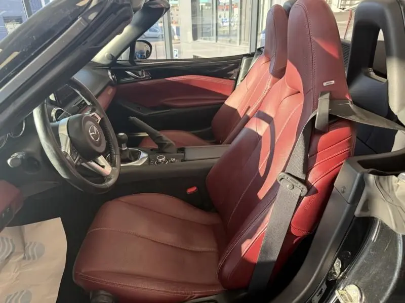 Intérieur de la Mazda MX-5 2020 noir, vue côté conducteur, sièges en cuir rouge et boîte manuelle visible.
