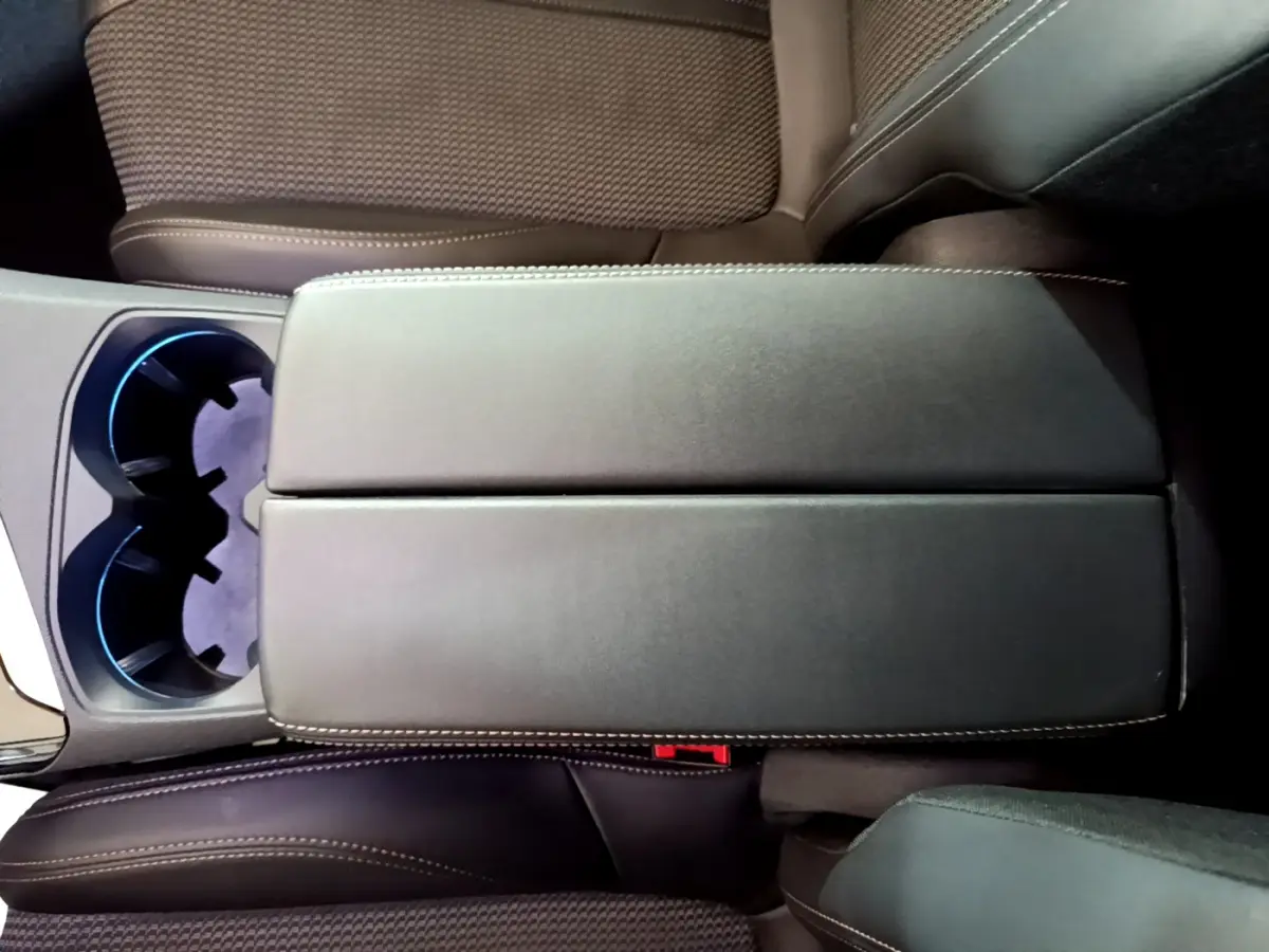 Vue plongeante sur l'accoudoir central noir et les sièges en tissu marron du Peugeot 3008 BlueHDi 130 GT 2023.