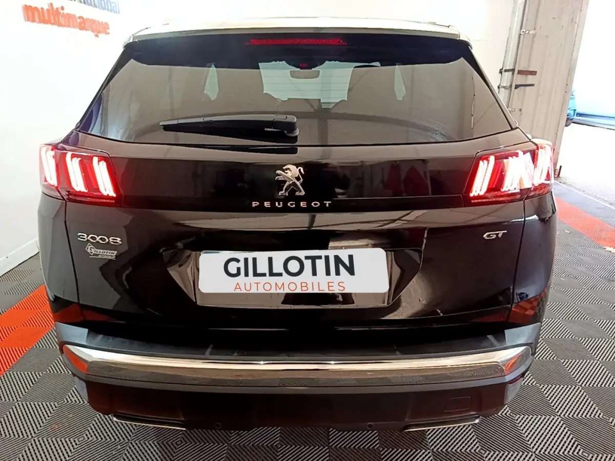 Vue arrière d'un Peugeot 3008 GT noir avec feux LED allumés et logo Peugeot visible sur le hayon.