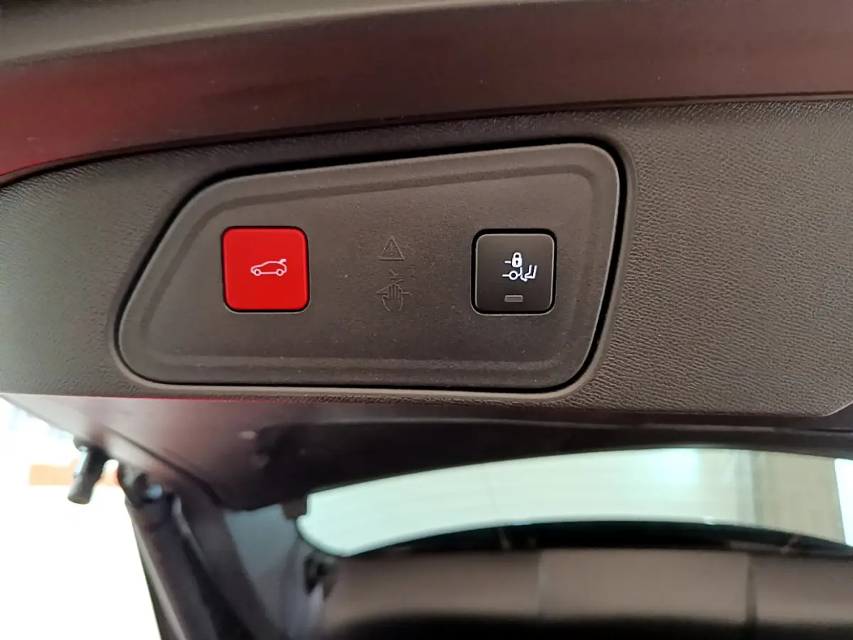 Boutons de commande rouge et noir pour ouverture et verrouillage du hayon, vue intérieure arrière du Peugeot 3008 noir.