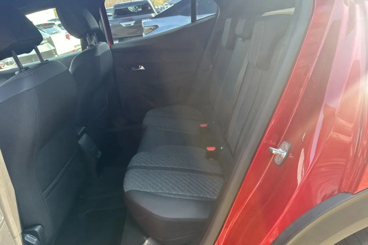 Vue côté arrière droit de l’habitacle d’un Peugeot 2008 rouge elixir, montrant la banquette arrière en tissu noir.