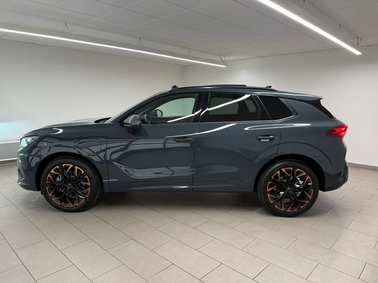 Vue de profil droit du CUPRA TERRAMAR 1.5 eHybrid bleu Fjord avec jantes cuivrées et toit ouvrant panoramique.