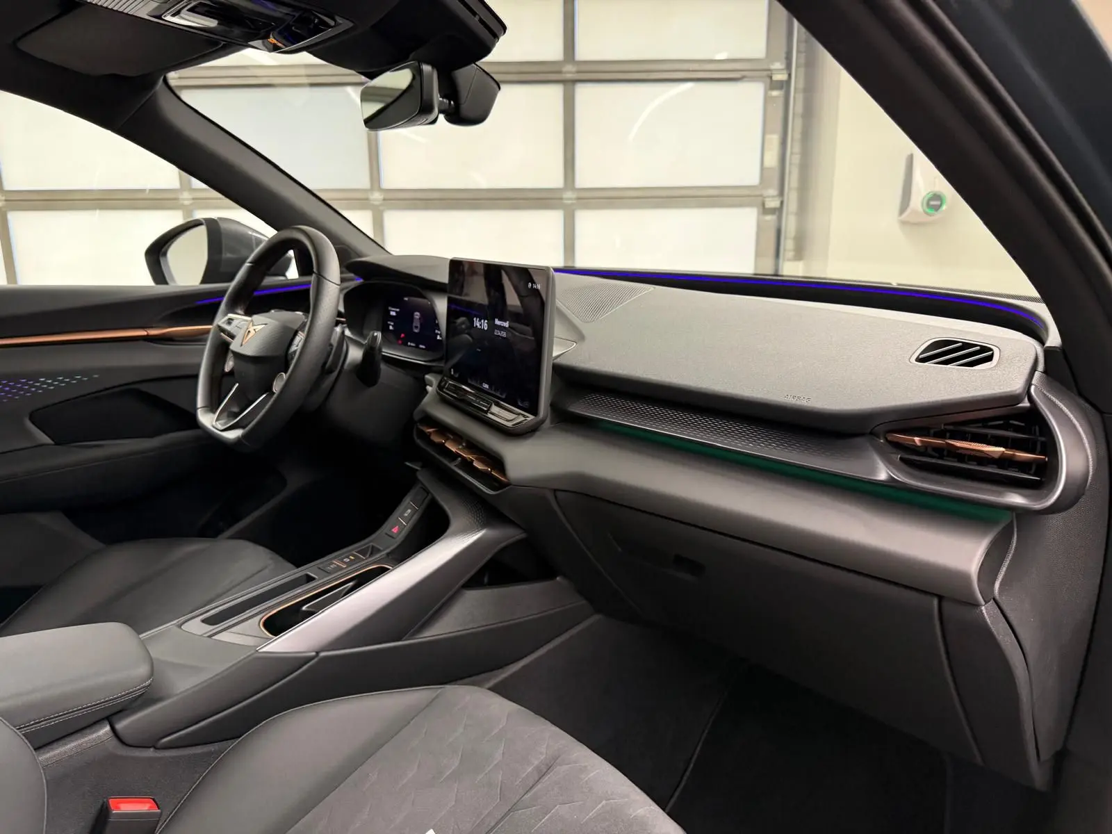 Vue intérieure côté conducteur du CUPRA TERRAMAR 2025, tableau de bord moderne avec éclairage d’ambiance cuivré et écran tactile central.
