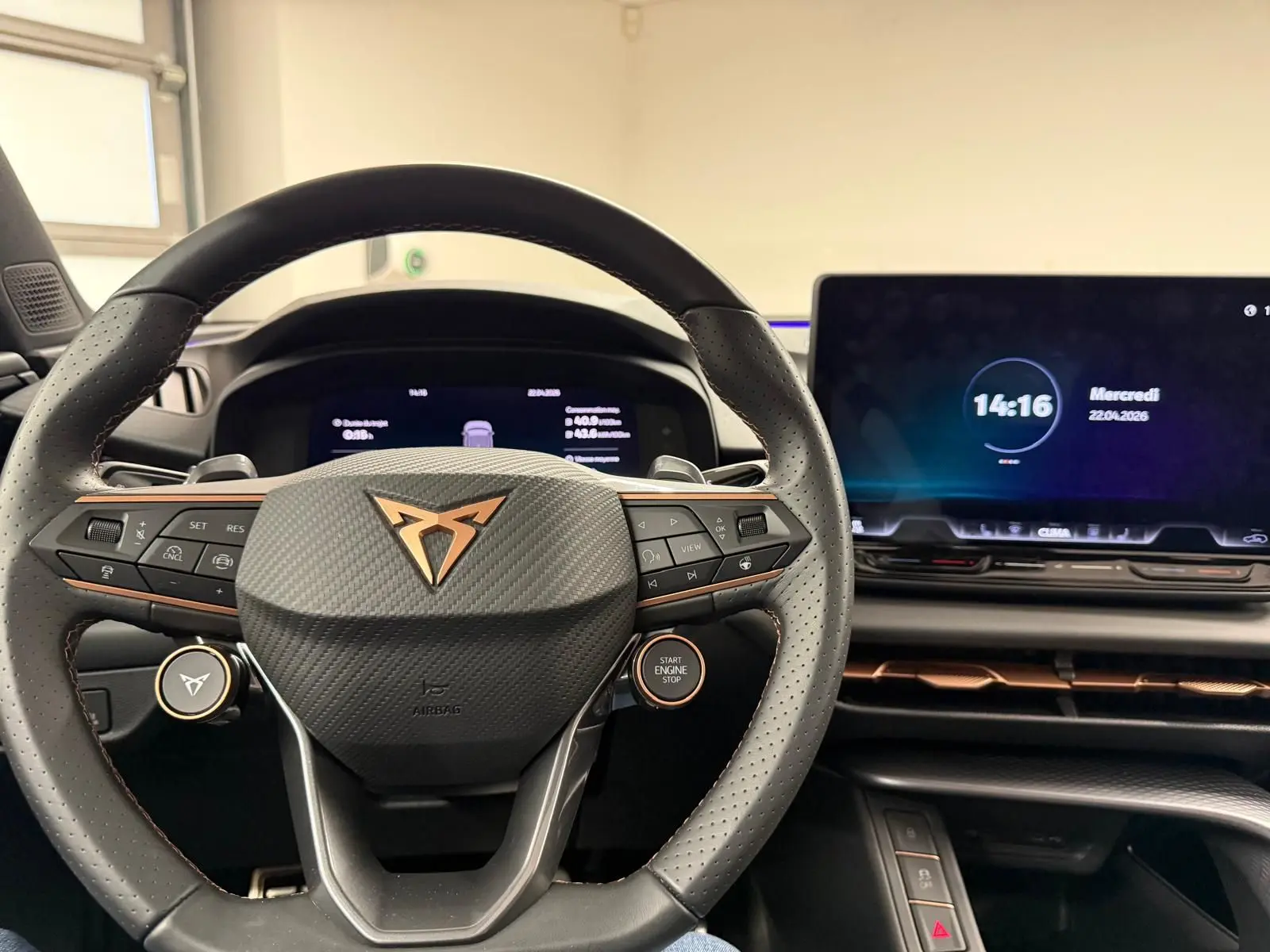 Vue intérieure centrée sur le volant perforé avec logo cuivré et tableau de bord numérique du CUPRA Terramar 2025.