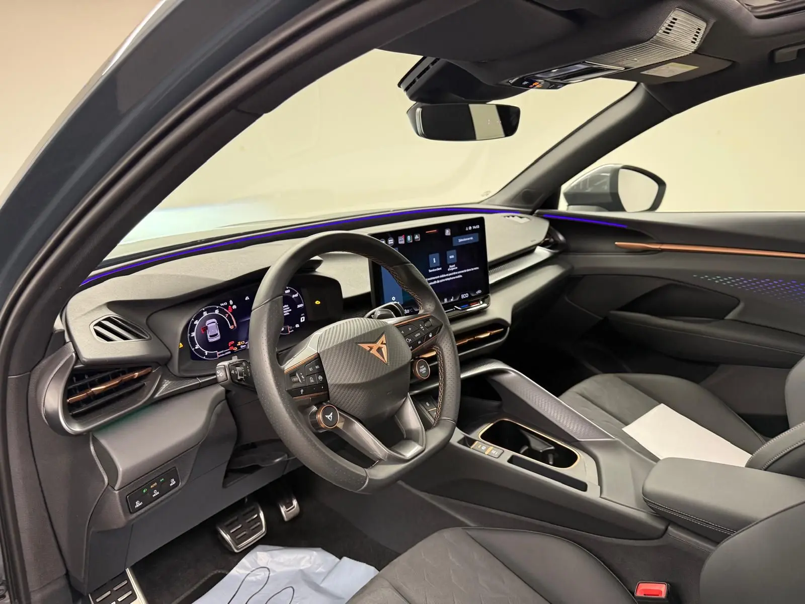 Vue intérieure côté conducteur de la CUPRA TERRAMAR 1.5 eHybrid avec tableau de bord numérique et éclairage d'ambiance violet.