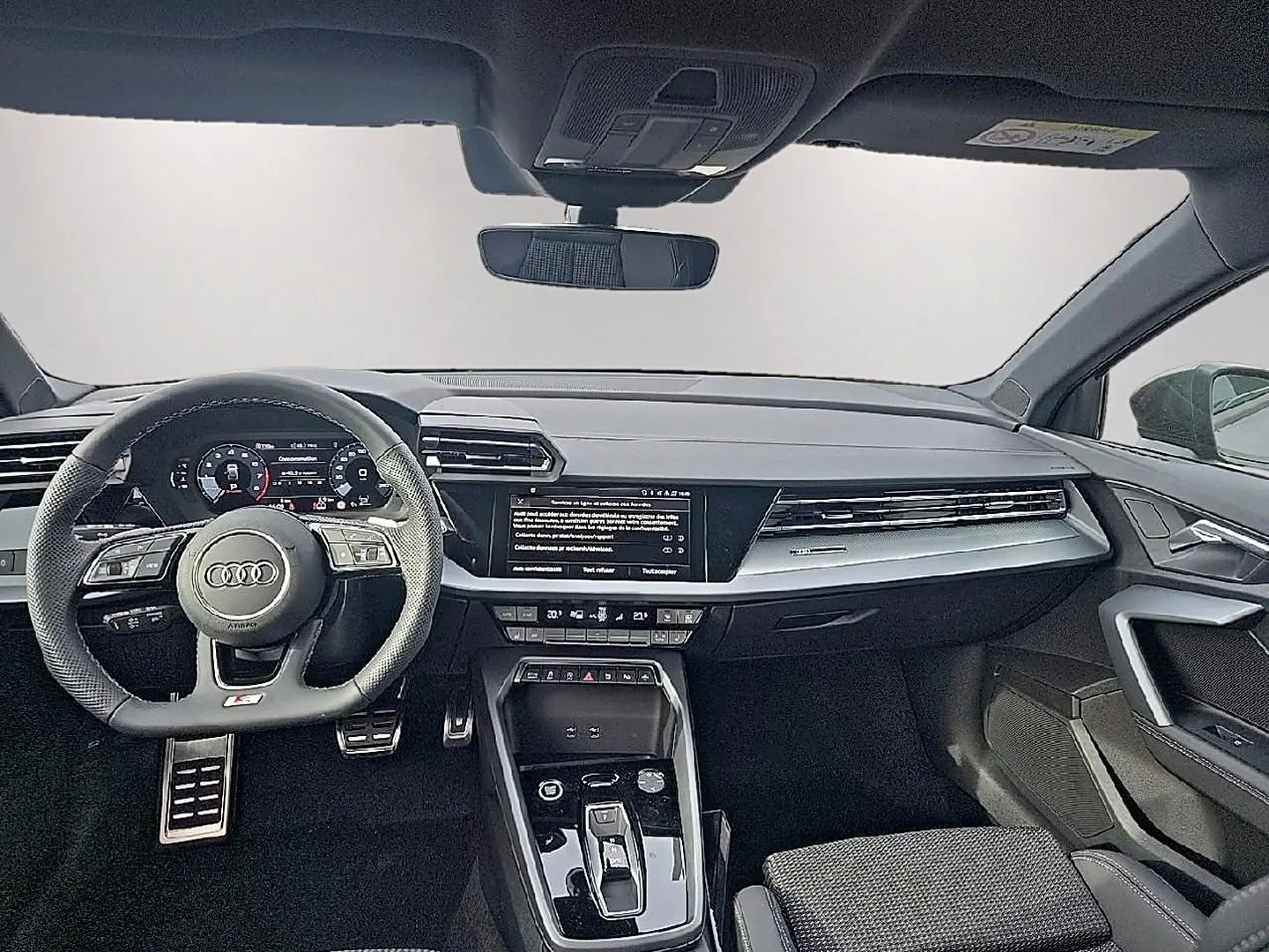 Vue intérieure avant de l'Audi A3 Sportback 2026, tableau de bord noir avec volant sport multifonction et écran central tactile.