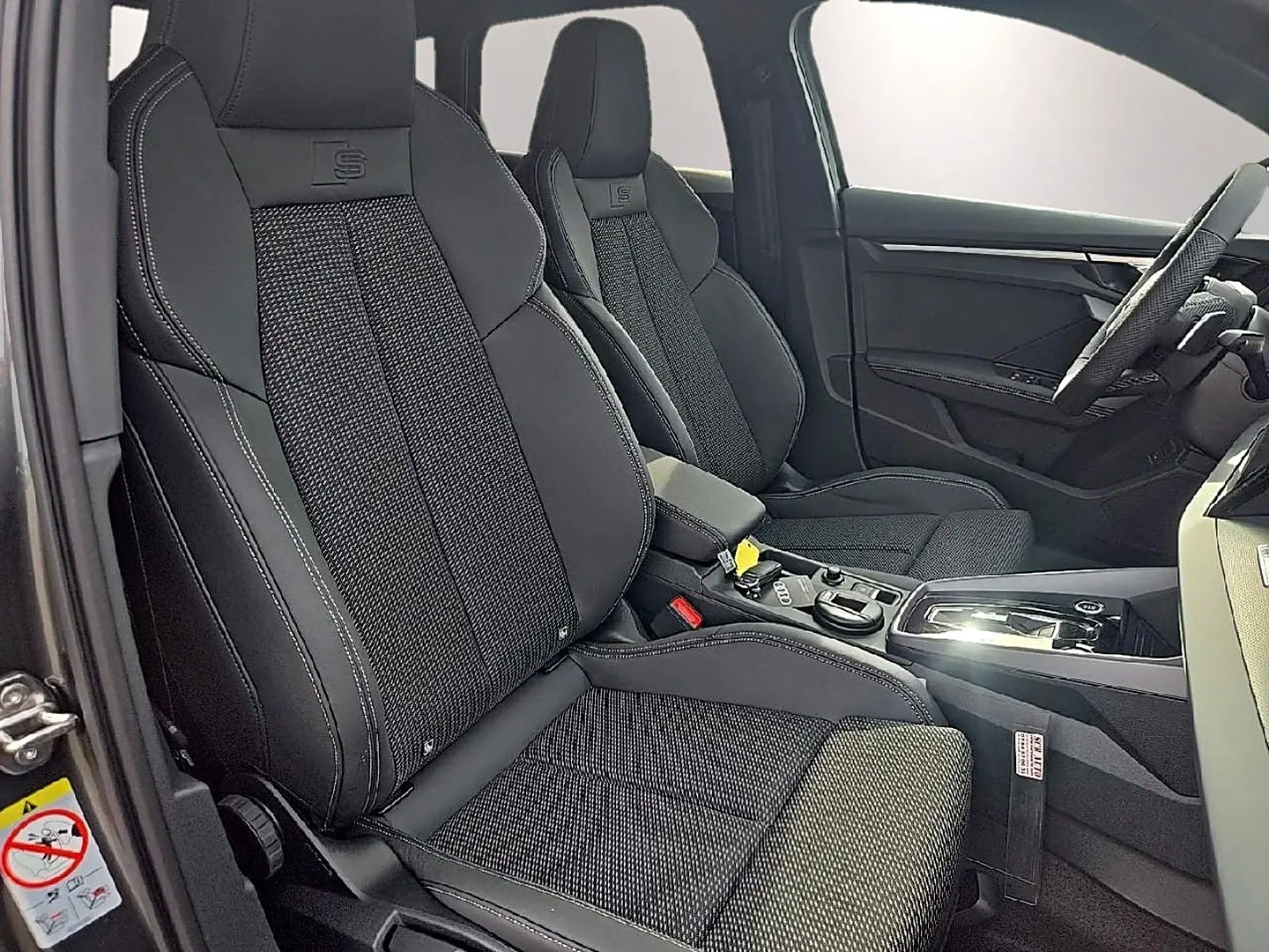 Intérieur avant d'Audi A3 Sportback 2026, vue côté conducteur, sièges sport noirs avec surpiqûres blanches et logo S.