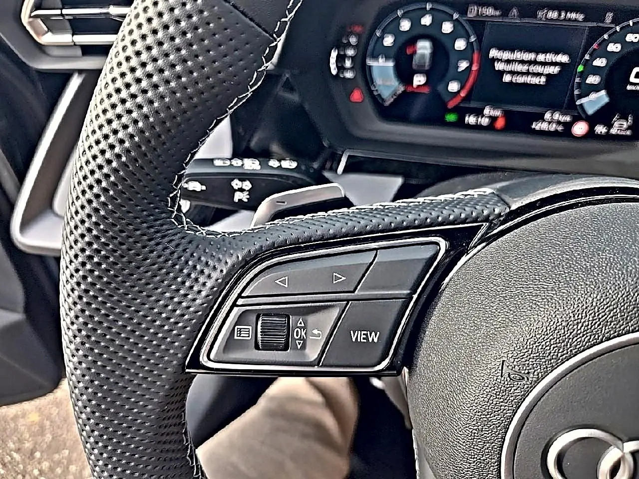 Gros plan sur le volant cuir perforé de l'Audi A3 Sportback 2026 avec commandes multifonctions et tableau de bord numérique.