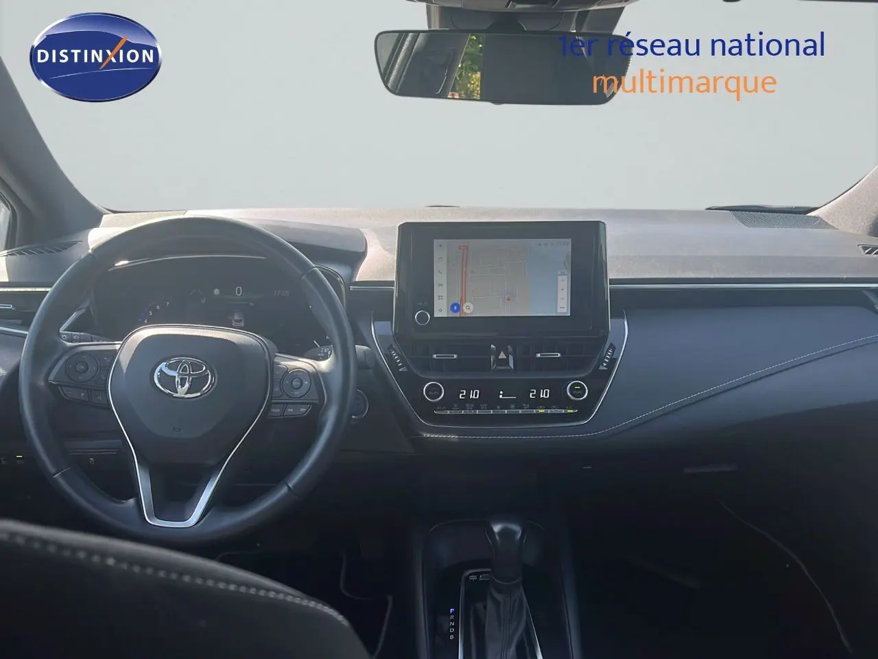 Vue intérieure frontale du tableau de bord et volant noir de la Toyota Corolla 2023 avec écran tactile et commandes intégrées.