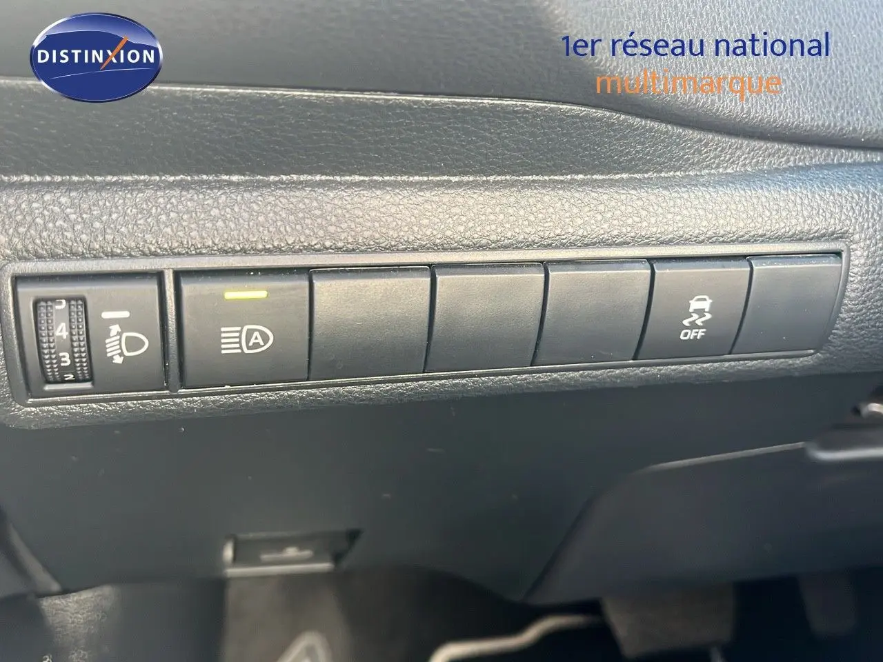 Gros plan sur les commandes de réglage des phares et de l'ESP dans l'habitacle d'une Toyota Corolla blanche 2023.