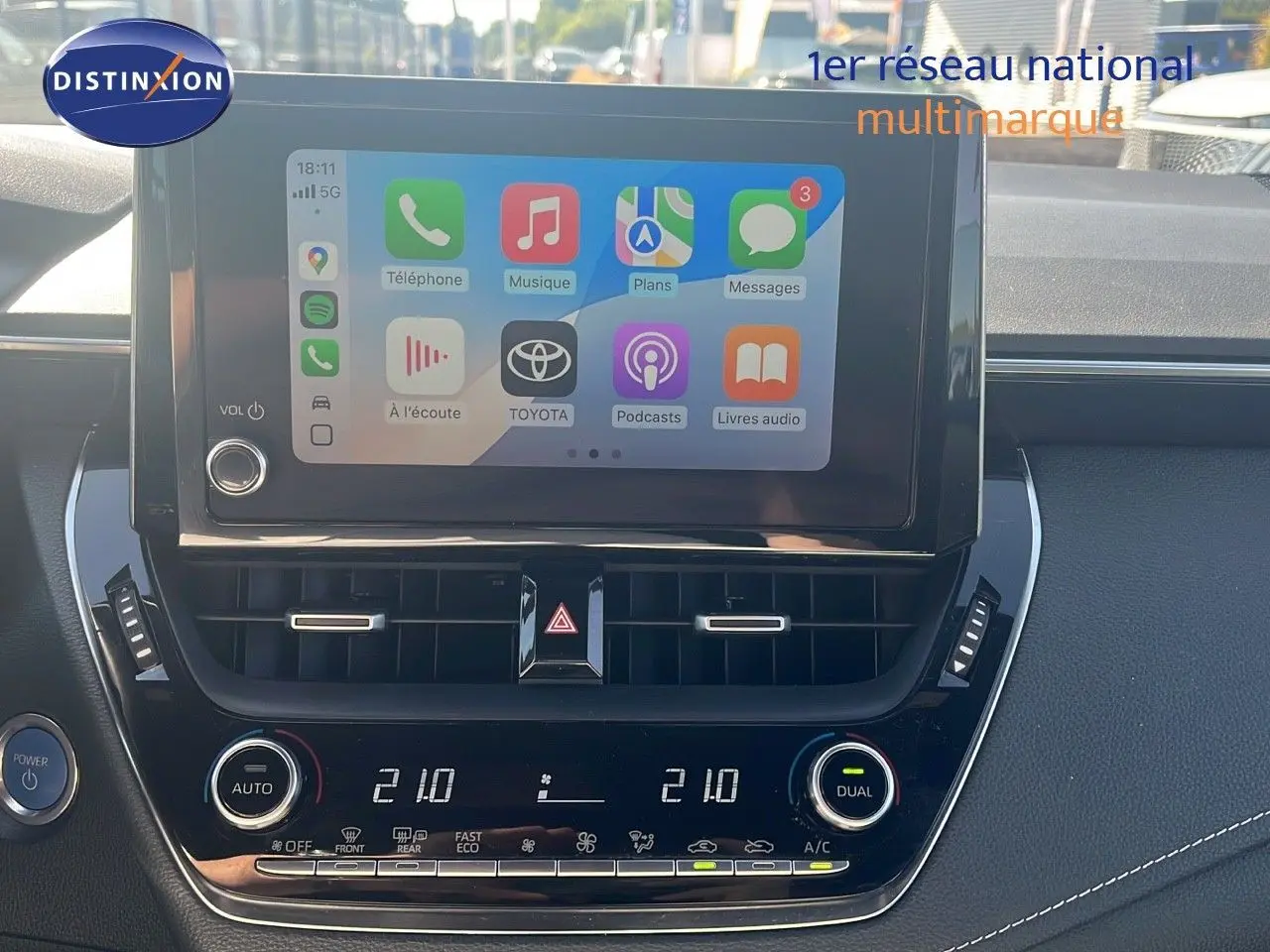 Écran tactile central affichant des applications, tableau de bord noir avec commandes climatisation sur Toyota Corolla hybride 2023.