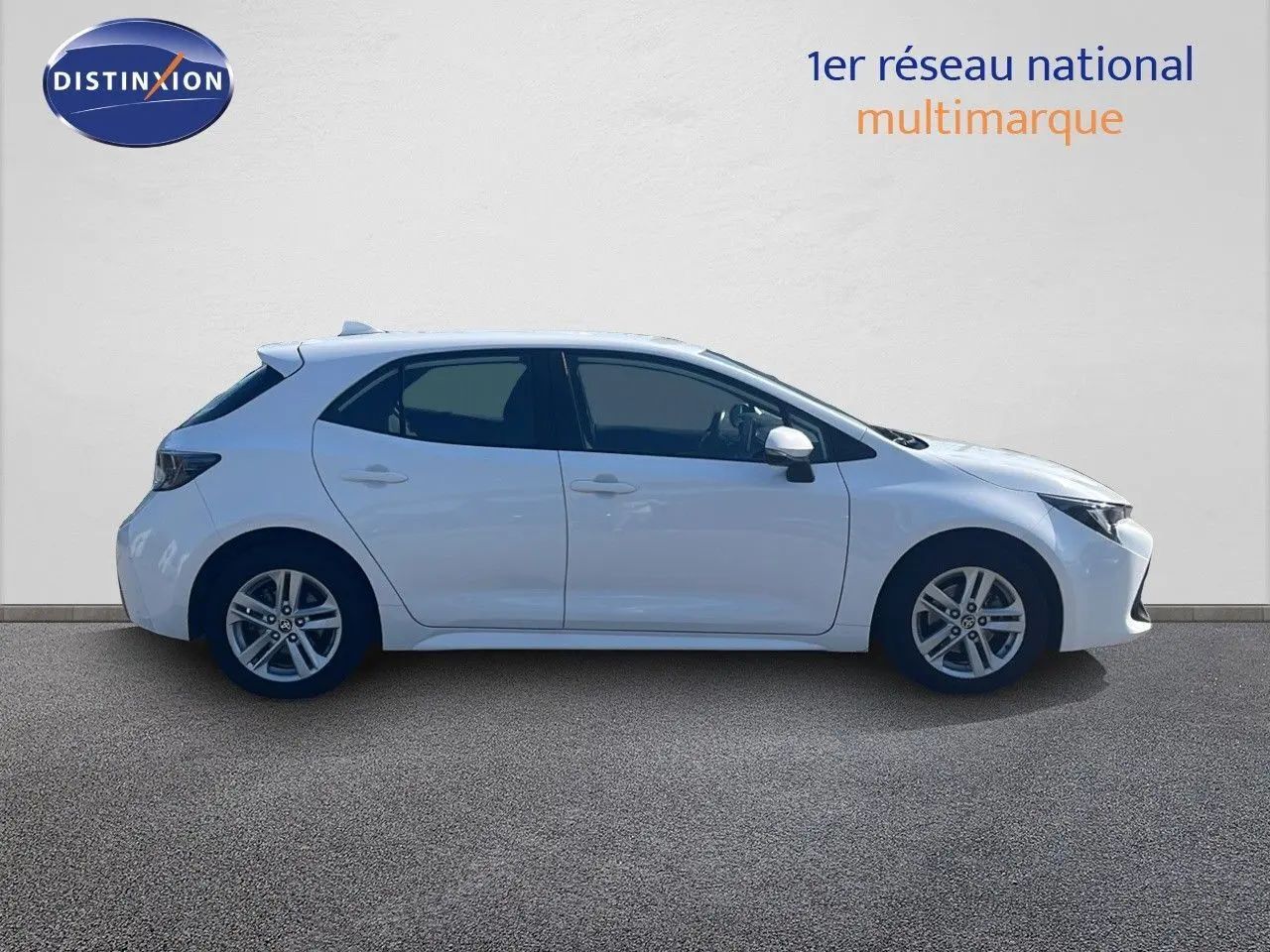 Profil droit d'une Toyota Corolla 1.8 HSD 122CH CVT Dynamic blanche pure, cinq portes, sur fond neutre.