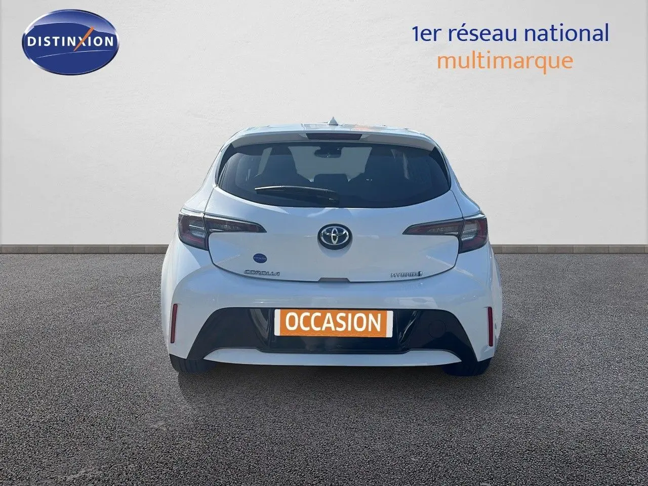Vue arrière d'une Toyota Corolla blanche pure 2023 hybride avec plaque "OCCASION" sur fond neutre.