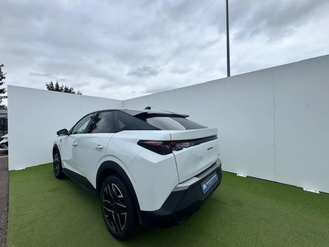 Vue 3/4 arrière gauche d'un Peugeot 3008 blanc nacré avec toit noir et jantes alliage noires sur fond extérieur.