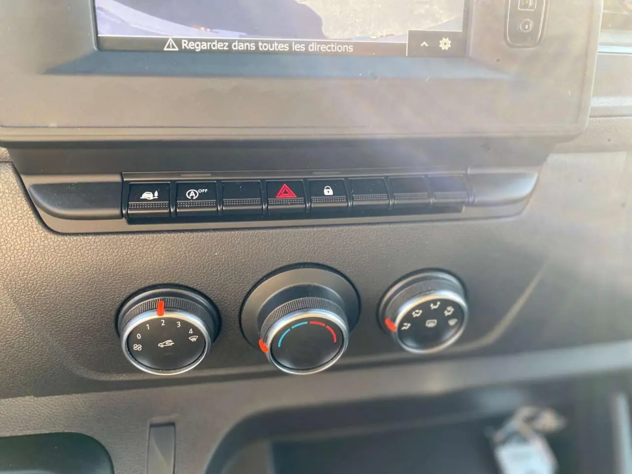 Gros plan sur les commandes de climatisation et les boutons de fonction du tableau de bord de l'Opel Movano Fourgon blanc.