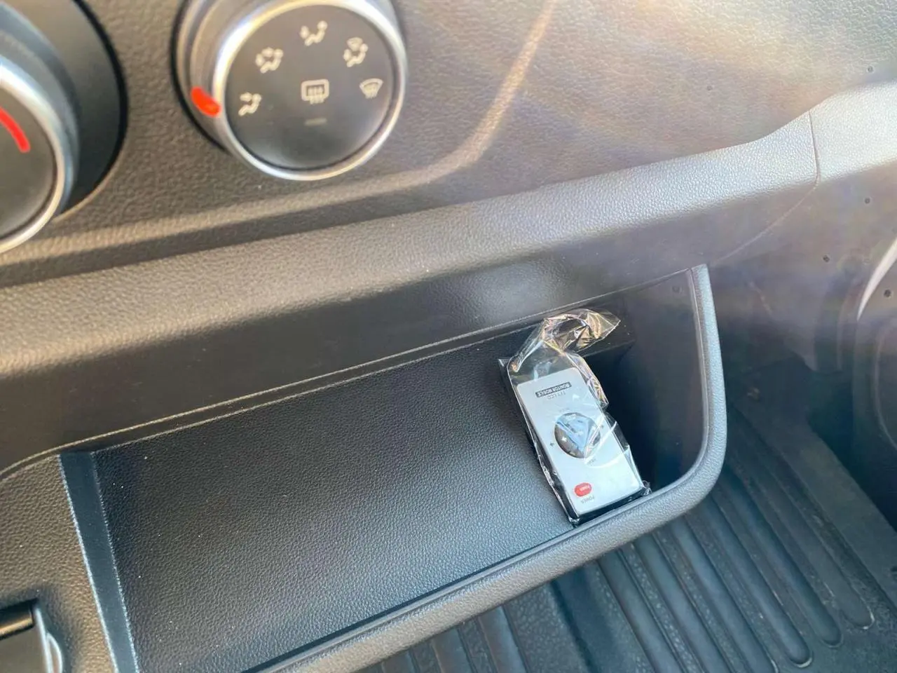 Gros plan sur la console centrale noire de l'Opel Movano Fourgon 2021 avec une télécommande emballée visible.