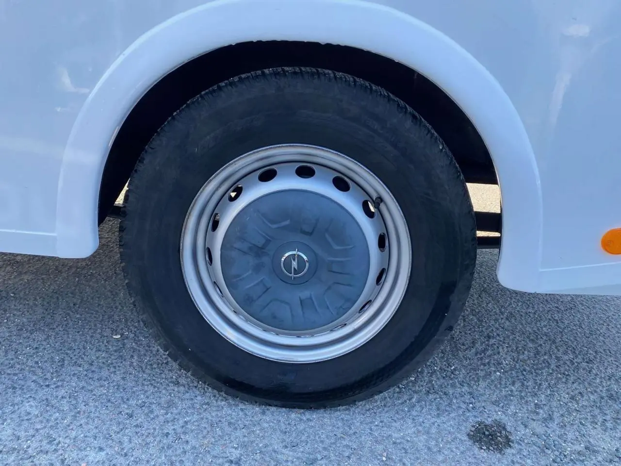 Gros plan sur la roue avant gauche blanche d'un Opel Movano Fourgon 2.3 CDTI avec jante acier et logo Opel central.