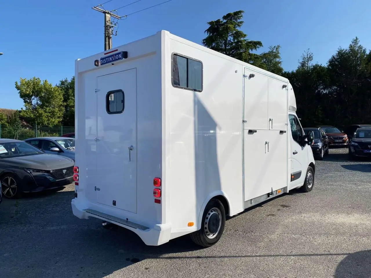 Vue 3/4 arrière droite d'un Opel Movano Fourgon blanc avec porte arrière et fenêtres latérales pour chevaux.