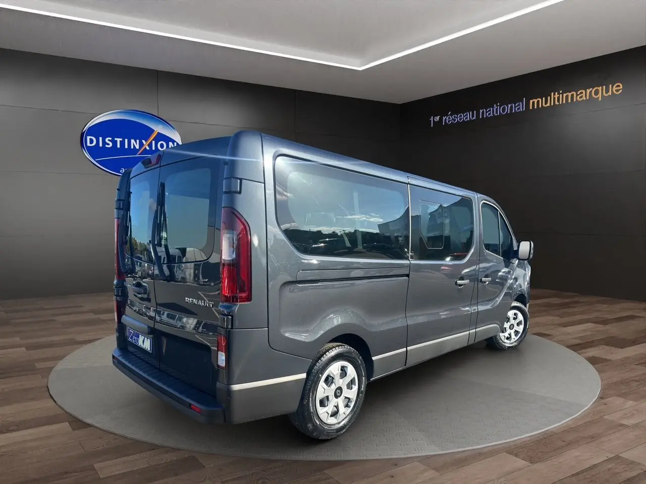 Renault Trafic Combi gris comète vu en 3/4 arrière droit, porte latérale coulissante et vitres teintées visibles.