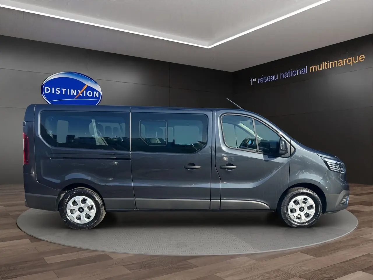 Profil côté droit du Renault Trafic Combi gris comète 2025 avec portes coulissantes vitrées et roues tôlées 16 pouces.