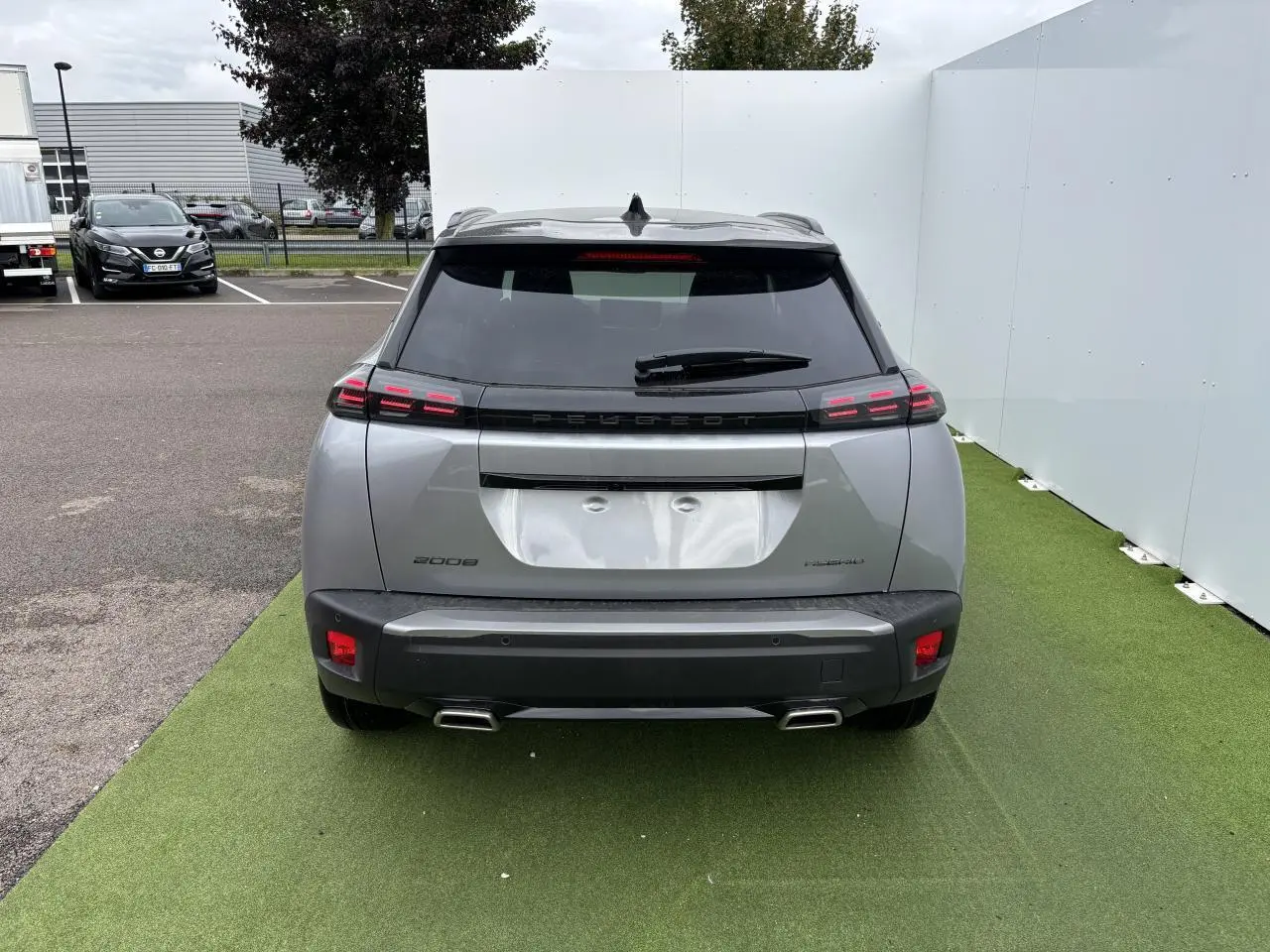 Vue arrière d'un Peugeot 2008 gris Artense avec toit noir, feux LED 3 griffes et double sortie d'échappement chromée.