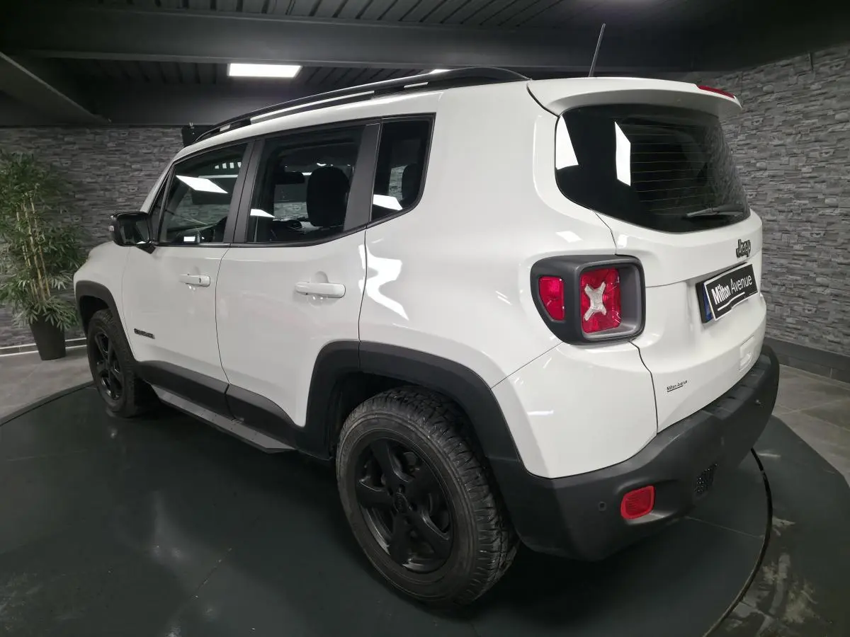 Jeep Renegade blanc vu en 3/4 arrière droit avec jantes noires 5 branches et barres de toit gris clair.